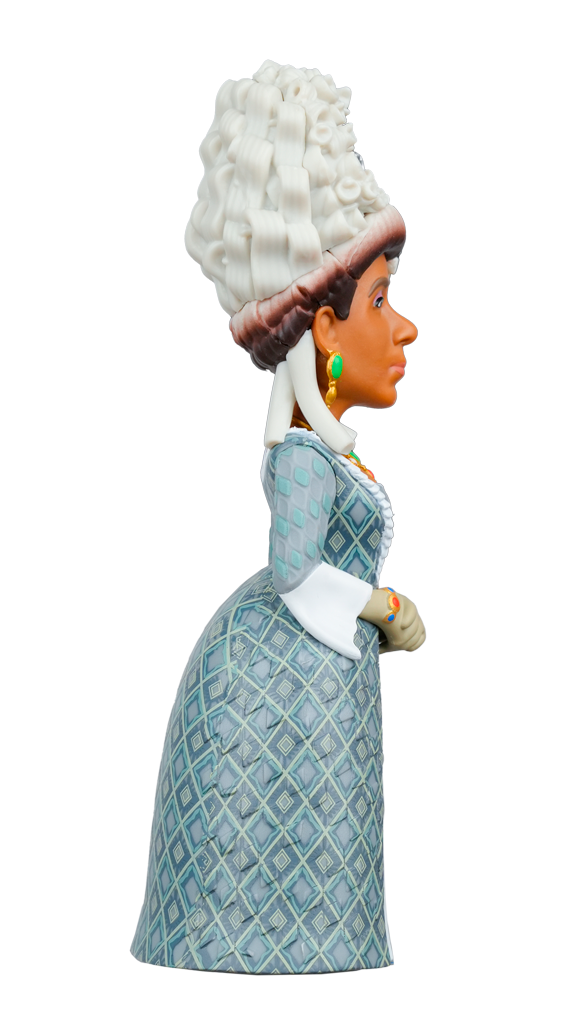 The MINIX Bridgerton Queen Charlotte Figure shows a woman with dark skin, a large white wig, green earrings, and a blue diamond-patterned dress