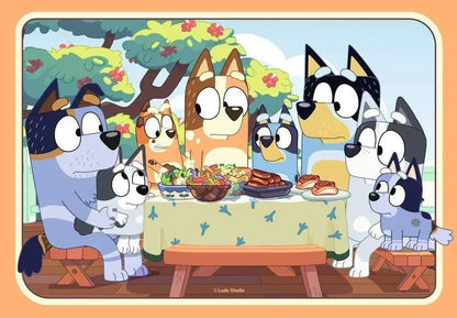 Artwork showing the entire Bluey extended family of eight dogs having an outdoor picnic gathered around a table piled high with delicious food