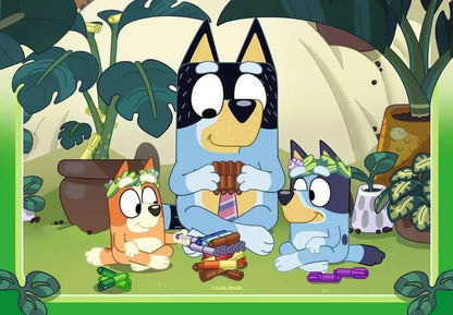 The Bluey family sits in a vibrant garden, with Bandit playing a pan flute and Bluey and Bingo wearing floral crowns surrounded by colorful sticks