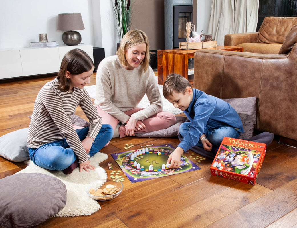 Family playing Midnight Market board game on a wooden floor with cookies and pillows