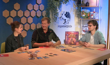 The Boss Fighters board game box stands prominently on a light wooden table where three players are actively enjoying the game during a Pegasus Spiele stream event