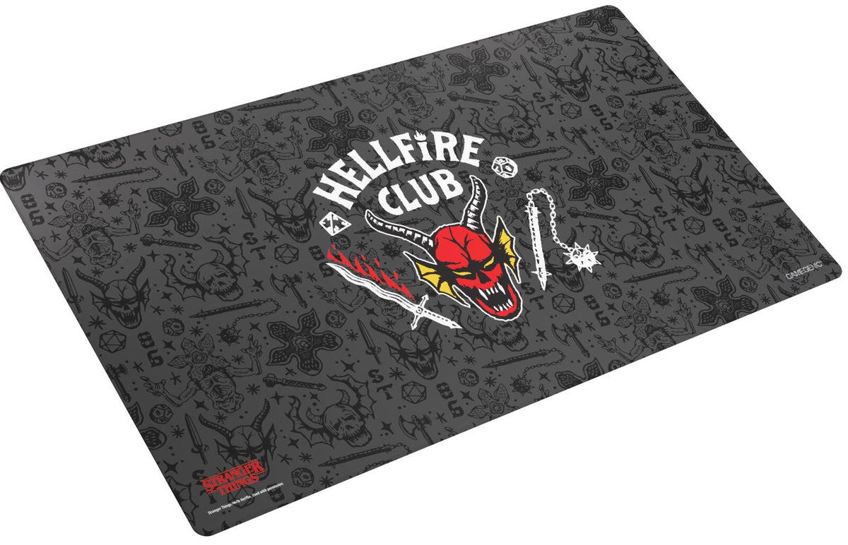 Hellfire Club gaming mat with a red demon logo, sword, and flail, patterned with Demogorgon heads, skulls, weapons, and D&amp;D dice on a dark background