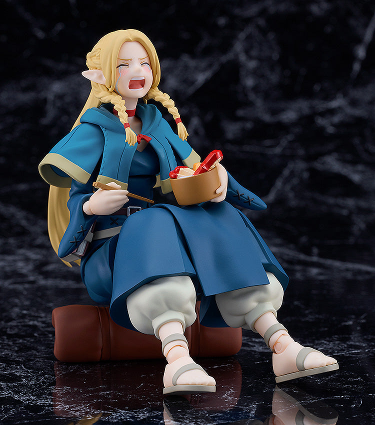 Good Smile Company Delicious in Dungeon Figma Marcille figure posed seated wearing a blue hooded outfit and white sandals holding a bowl of food and chopsticks