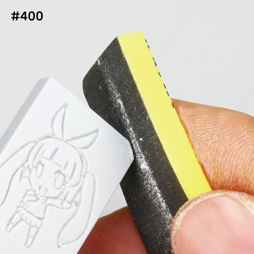 Hand sanding a white block with an engraved chibi anime character using a #400 grit sponge