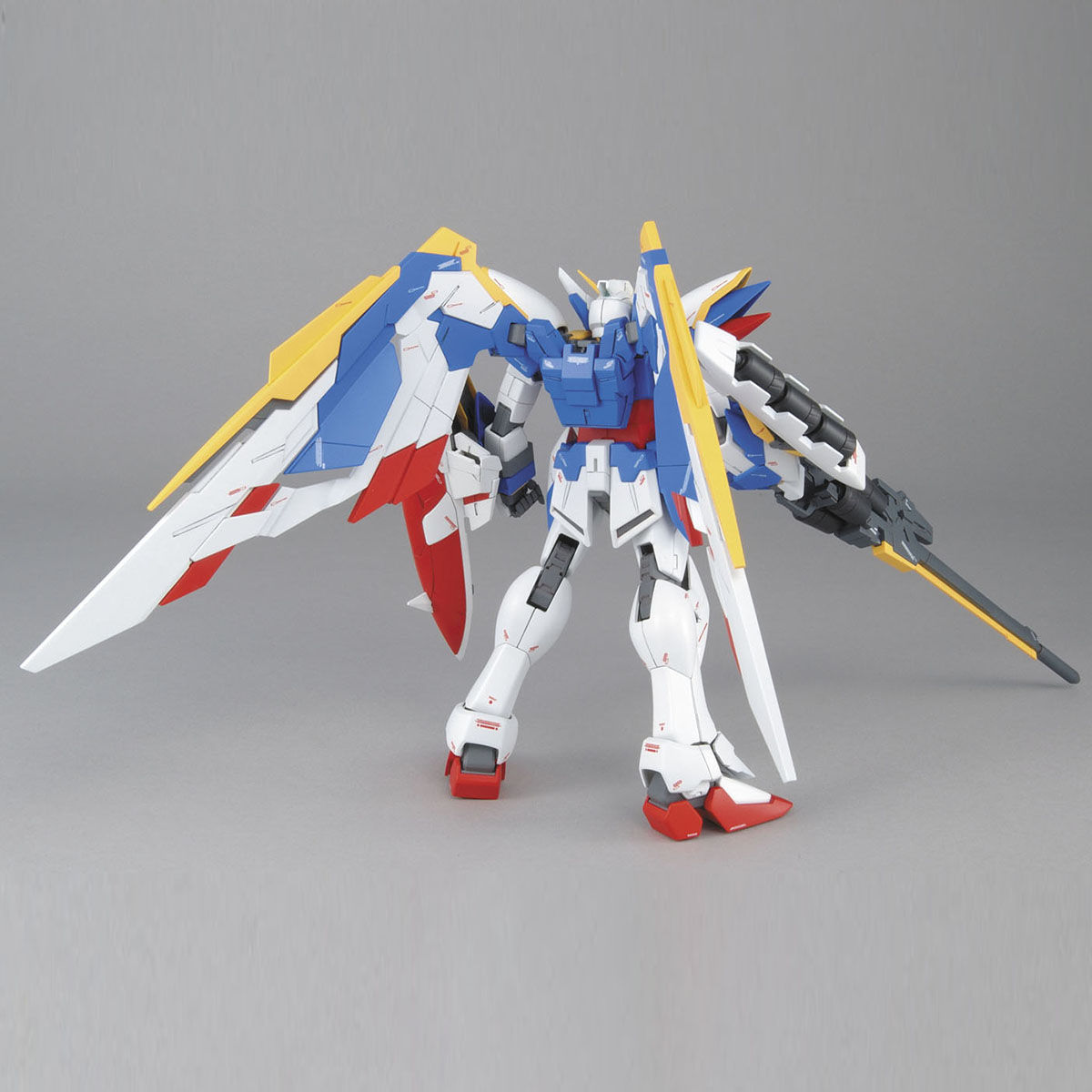 Multicoloured winged Gundam model kit, primarily white and blue, standing and holding a long rifle