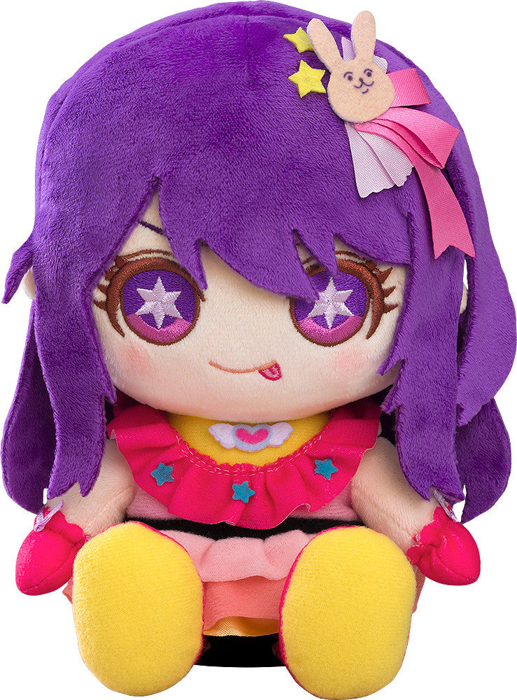A vibrant anime girl plush toy with purple hair, bunny clip, starry purple eyes, tongue out, and a ruffled pink and yellow dress