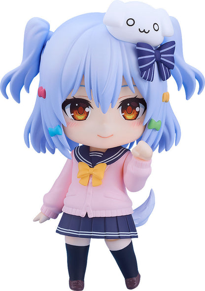 A chibi anime girl figure with blue pigtails, pink cardigan, sailor uniform, white dog accessory, smiling, and waving