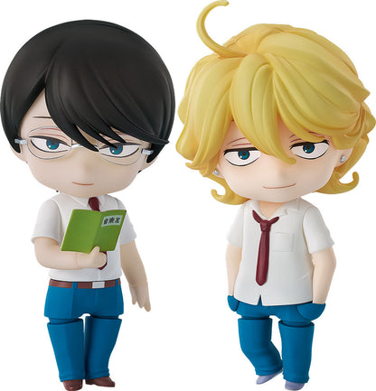 Two Nendoroid anime figures. One with black hair & glasses holds a book; the blonde-haired one smiles
