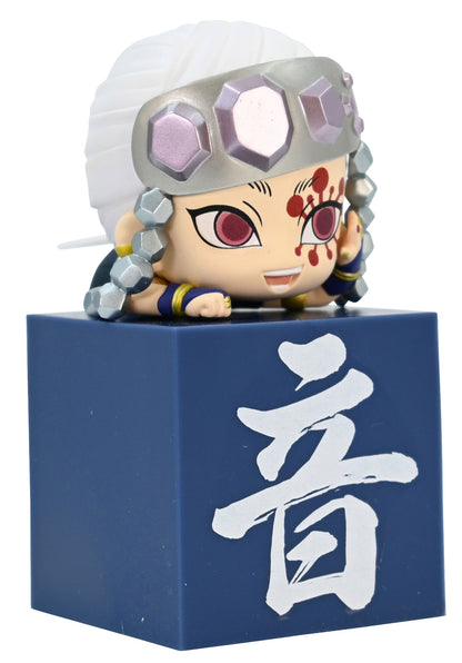 Chibi style anime figure with white hair and jeweled headband sitting on a blue block with a white Japanese character
