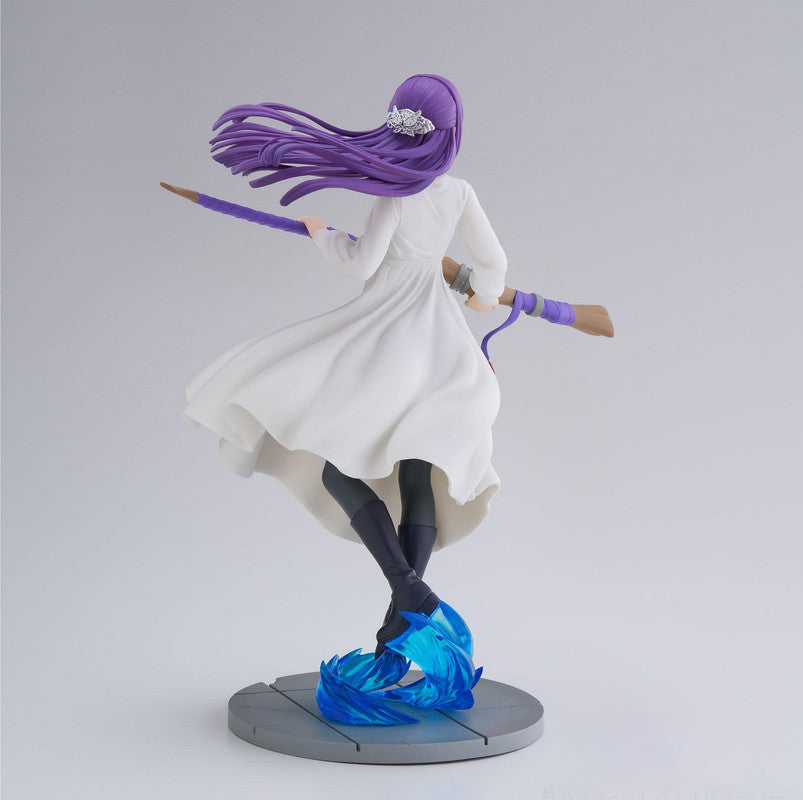 Back view of figure of a girl with long purple hair, wearing a flowing white dress, holding a large paintbrush staff stand on grey background
