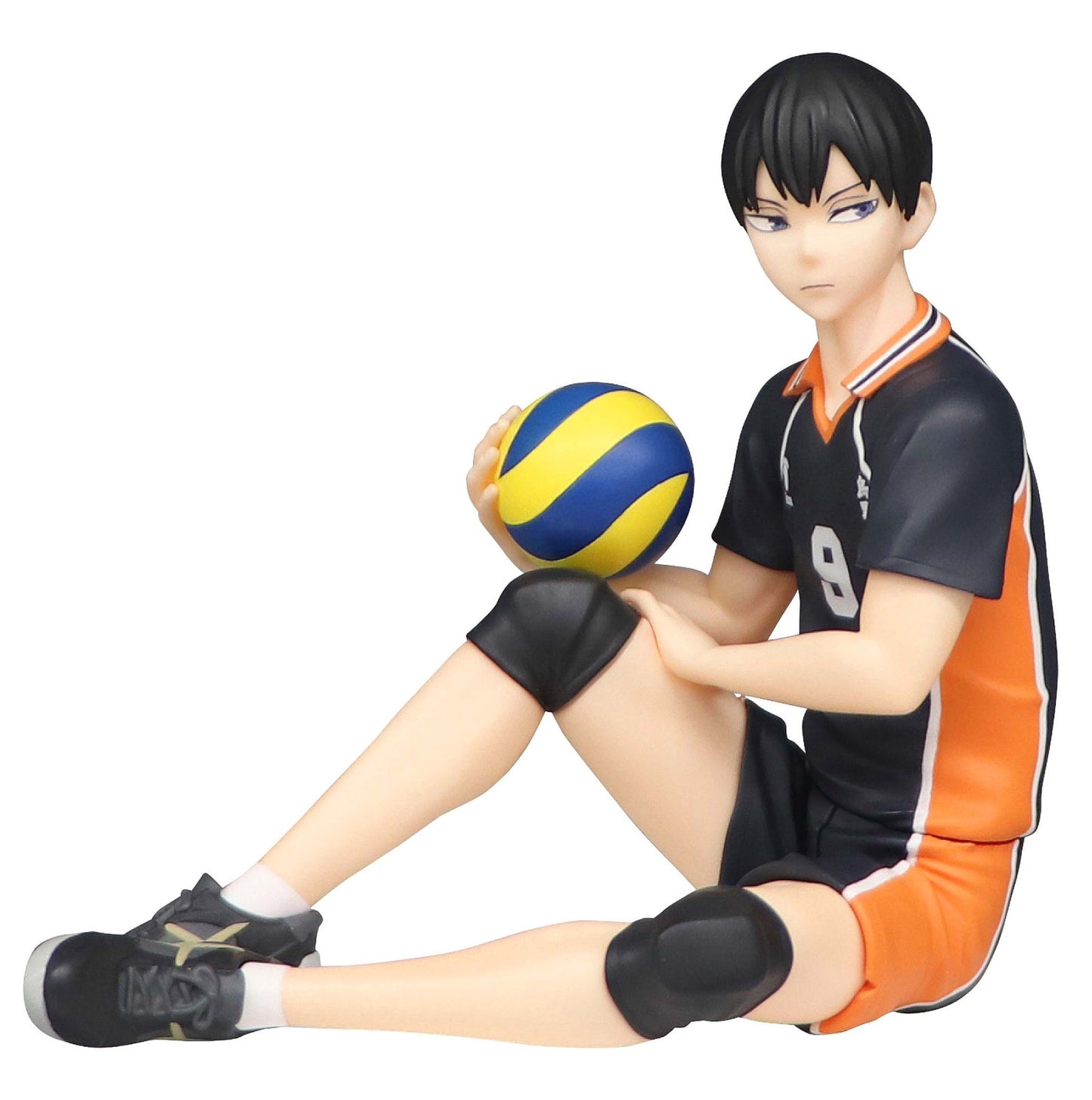 Figure of a young man in a black and orange volleyball uniform sitting and holding a blue and yellow volleyball