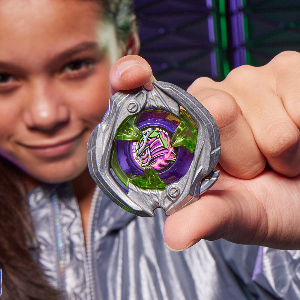 Smiling youth holds up a detailed purple and silver Beyblade top featuring a green and pink monster design