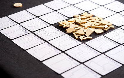 A grid of Tokyo Jutaku game cards with stylized city maps and names like Shinjuku and Shibuya surrounds a pile of beige wooden game pieces on a dark surface