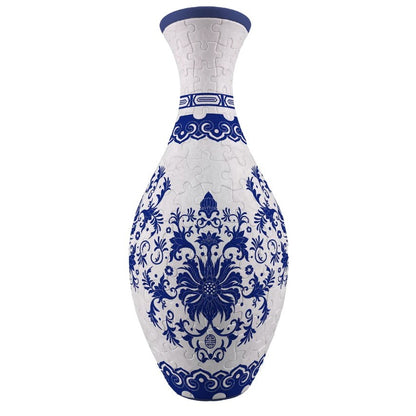 A white and indigo blue 3D puzzle vase featuring ornate floral and scroll patterns with visible puzzle piece connections forming its elegant bottle-like shape