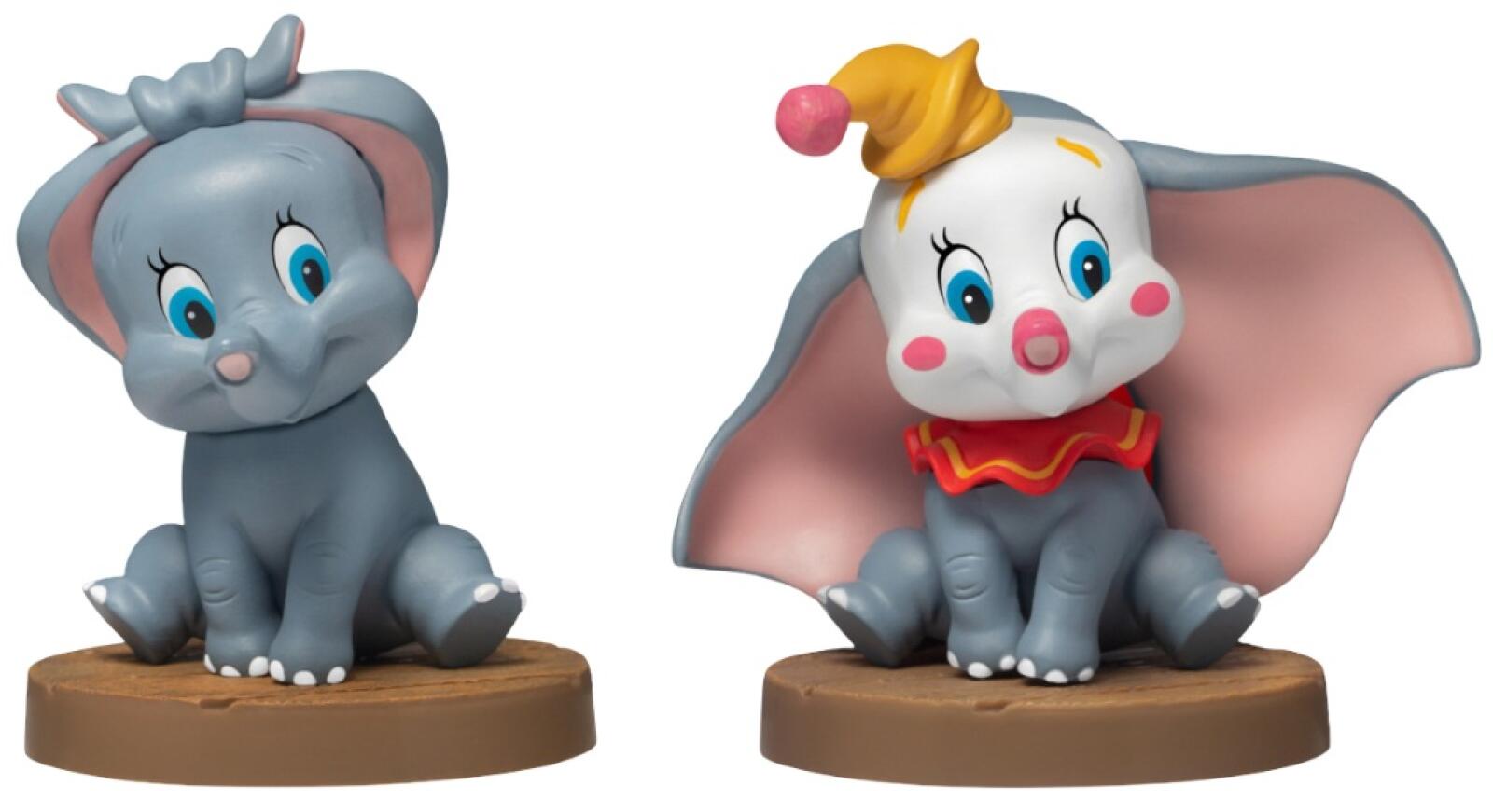 Two stylized Dumbo figures one in grey with a bow and one in a clown hat against red curtains