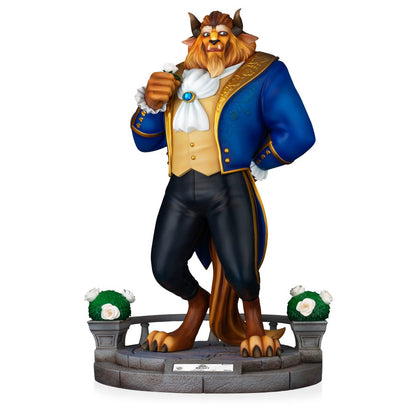 Disney Traditions Beast statue in royal blue jacket and gold trim holding a white rose on a stone base