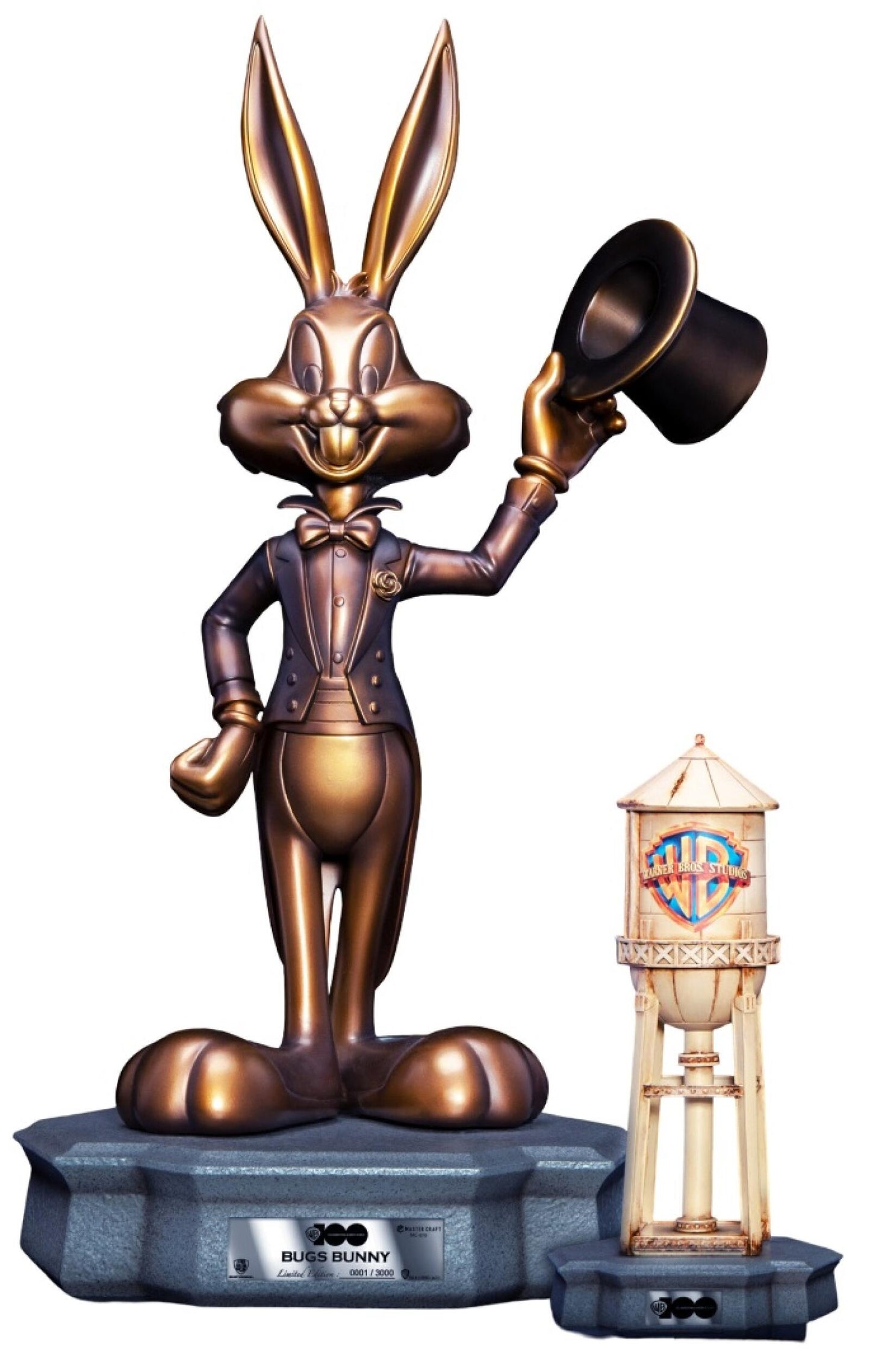 Bronze statue of Bugs Bunny in a tuxedo tipping his top hat stands on a stone base next to a miniature Warner Bros Studios water tower
