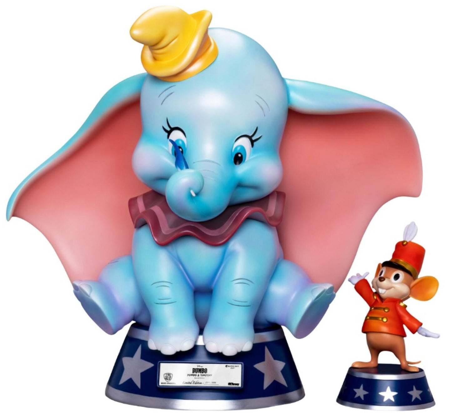 Detailed figurine of a light blue Dumbo elephant with large pink ears yellow hat and maroon collar sitting on a blue base with silver stars