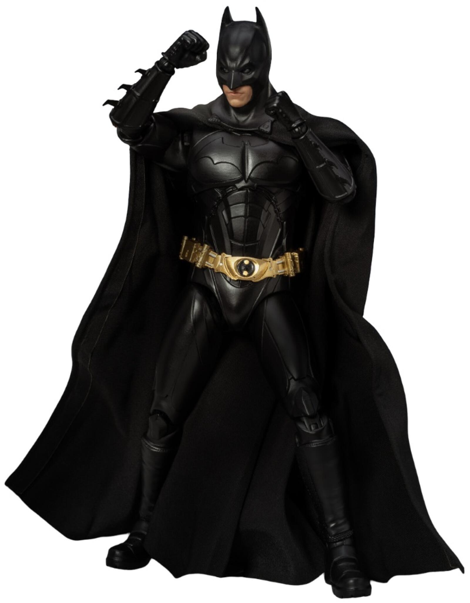 Batman action figure in black suit with golden belt standing with fists raised against backdrop of Gotham city and flock of bats at sunset