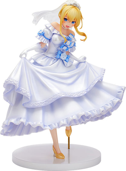 Blonde anime figure in a white, ruffled wedding dress with blue floral accents, tiara, and veil, smiling and holding up her skirt.