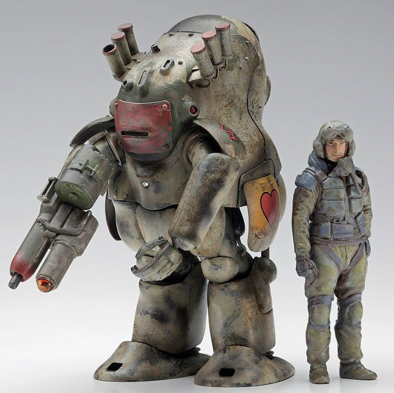 Weathered military mecha model standing next to a detailed pilot figure