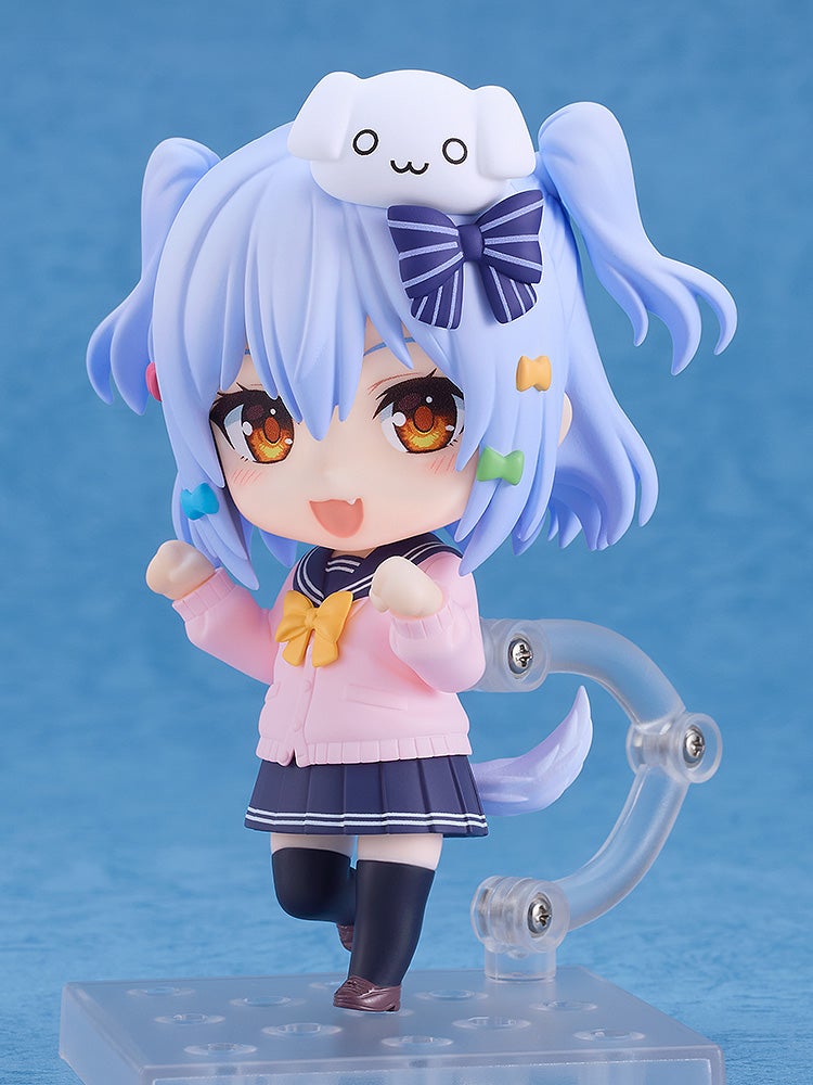Smiling anime girl figurine in a pink cardigan and navy school uniform, with blue pigtails and a white dog accessory