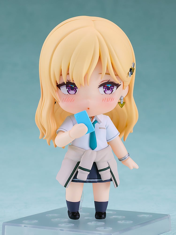 Chibi anime girl figure with blonde hair and school uniform, holding a blue smartphone to her mouth