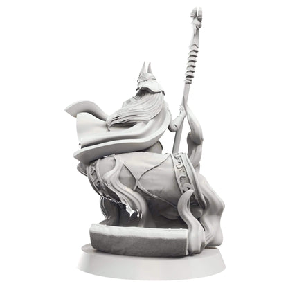 Grey fantasy miniature, back view. Character with horned helmet, long hair, flowing cape, seated and holding a tall staff.