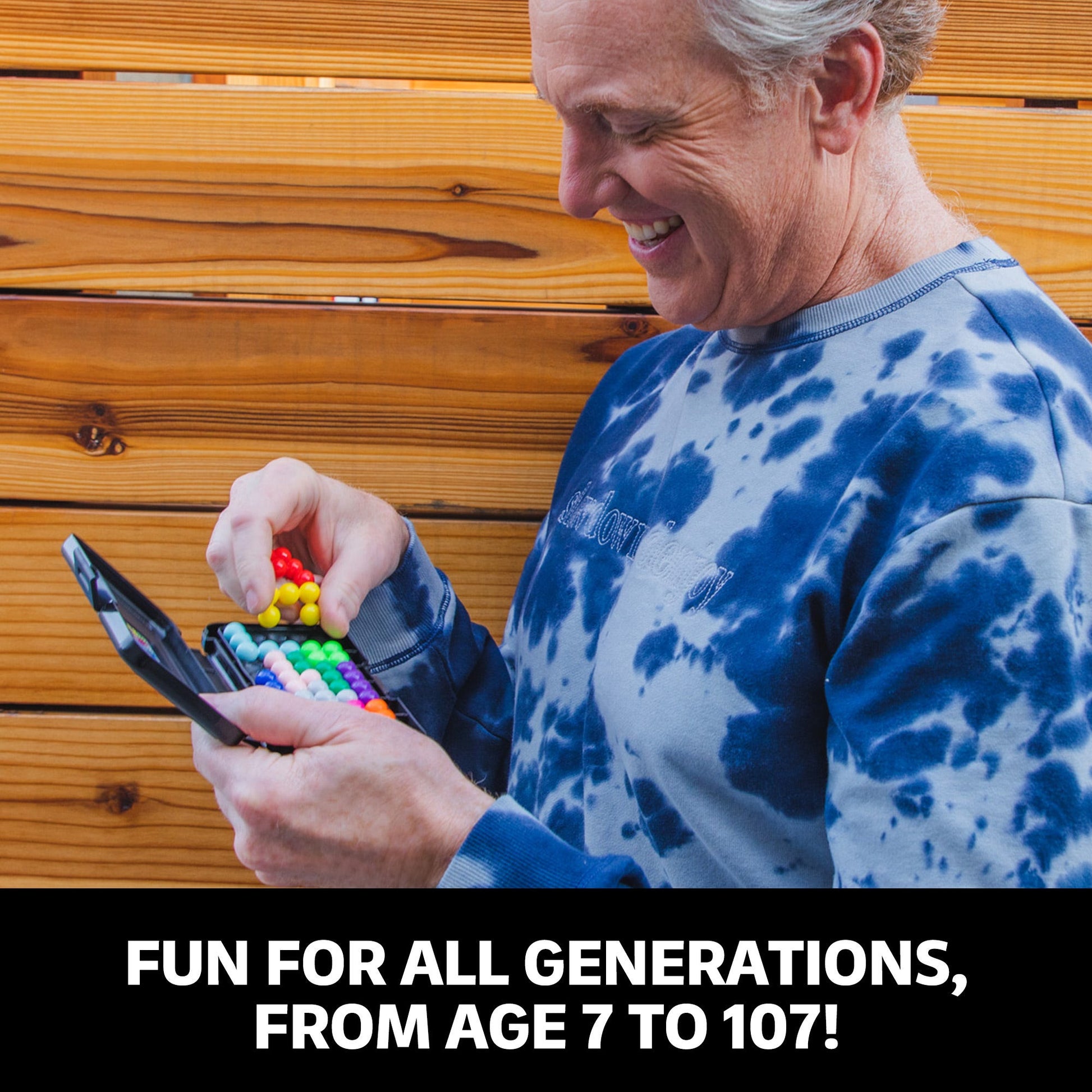Smiling man playing with colourful spherical puzzle beads contained in a black portable case