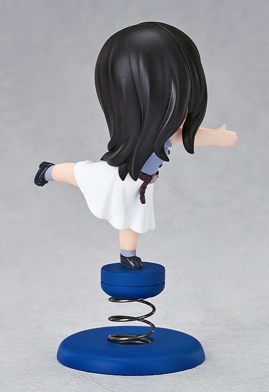 Side view of anime figure of a dark-haired girl in a blue and white dress balanced on a spring base