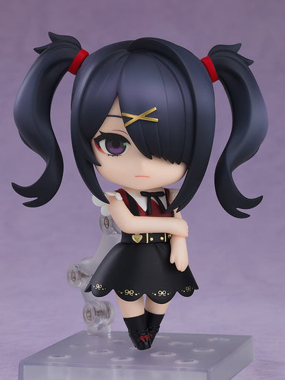 Nendoroid figure of a dark-haired girl with twin pigtails and a gold X clip, pouting in a black dress with arms crossed