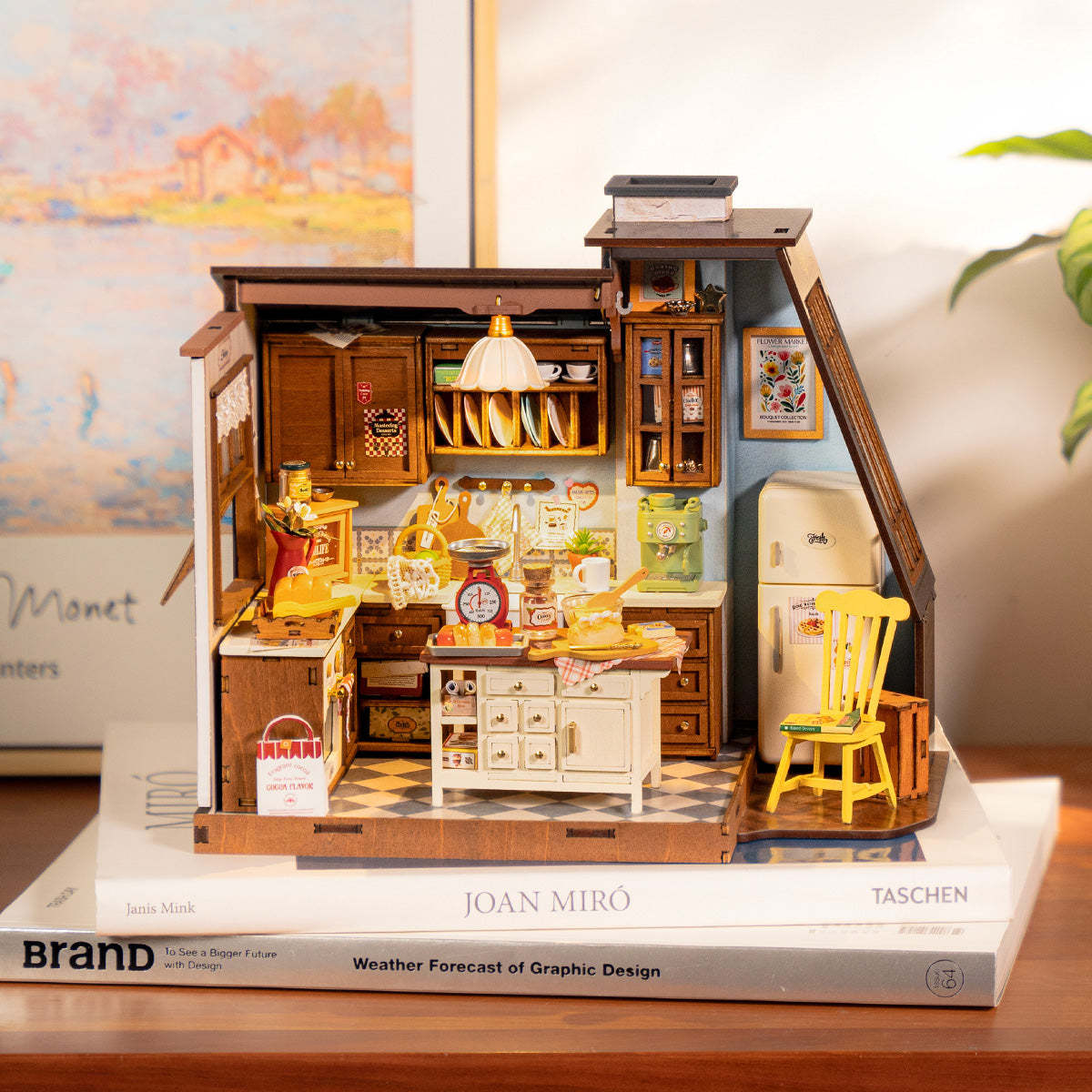 Detailed miniature wooden vintage kitchen model with a white island and accessories, sitting atop books