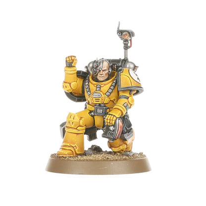 A miniature Legiones Astartes warrior in yellow power armor with a bionic eye kneels with a raised fist and a comms antenna on its back