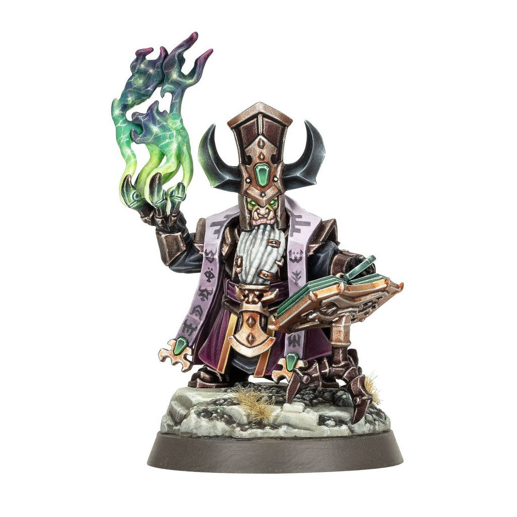 This Helsmiths Of Hashut Daemonsmith miniature features a white-bearded figure in dark armor and purple cloth casting a vibrant green spell while holding a mechanical grimoire