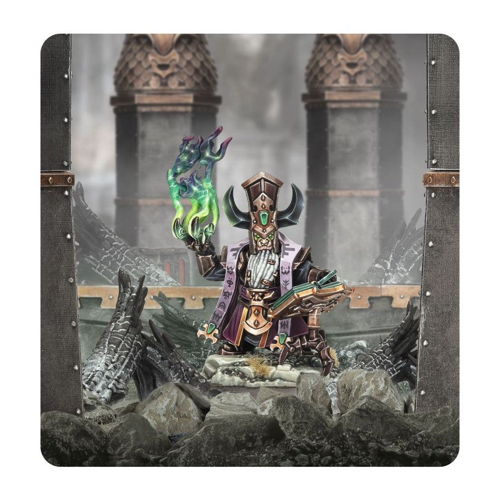 The Daemonsmith miniature, clad in purple robes and a horned hat, holds a tome and summons swirling green chaotic energy in a ruined setting