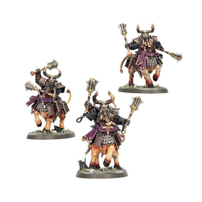 A trio of Helsmiths of Hashut Bull Centaur miniatures painted in black and purple armor, wielding large axes tipped with green gems