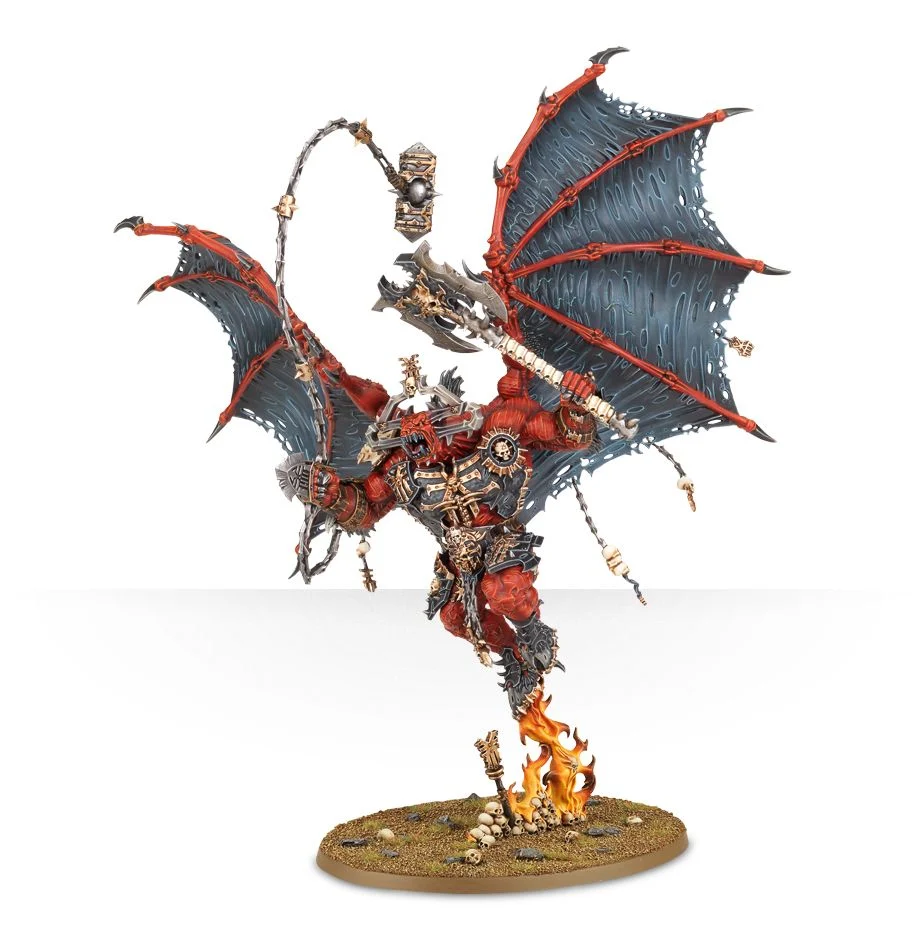 A painted miniature of a red Blades of Khorne Bloodthirster demon with large wings, black and gold armor, an axe, a spiked whip, and a base with skulls and fire