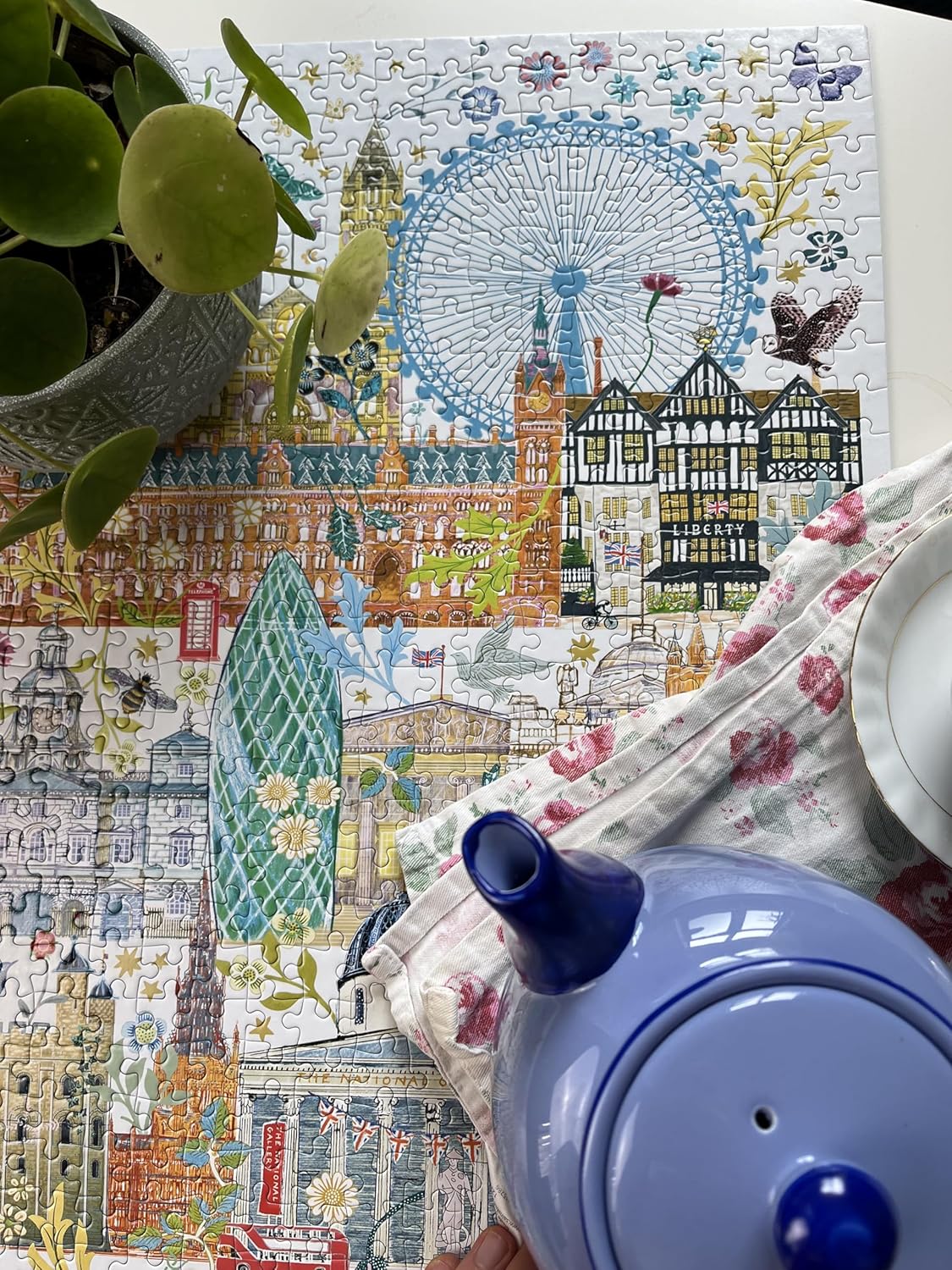 Close-up of a blue teapot and potted plant on a completed London landmark jigsaw puzzle illustration