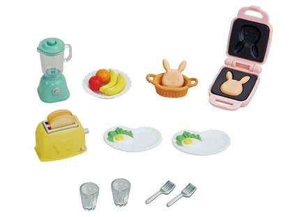 Miniature toy breakfast playset featuring a blender, toaster, bunny waffle maker, plates with eggs, fruit, and forks