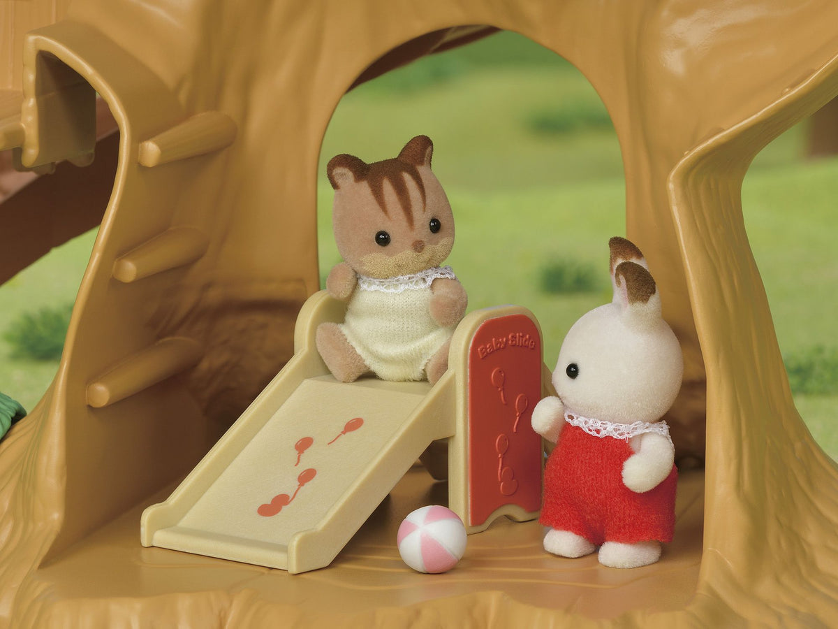 Flocked animal toys playing on a small playground slide within a tree playset
