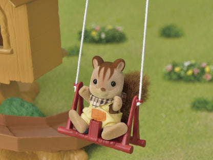 Flocked toy squirrel figure in yellow overalls sits on a red swing outdoors