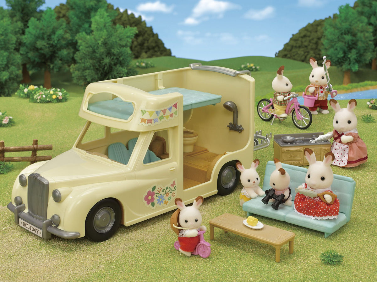 Toy rabbit figures from Sylvanian Families camping outdoors with a cream-coloured camper van