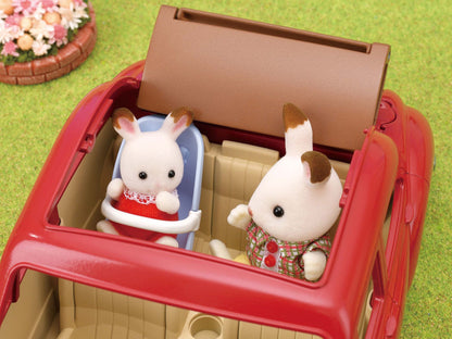 Two flocked rabbit figures sitting in a red toy convertible car, with one in a baby seat