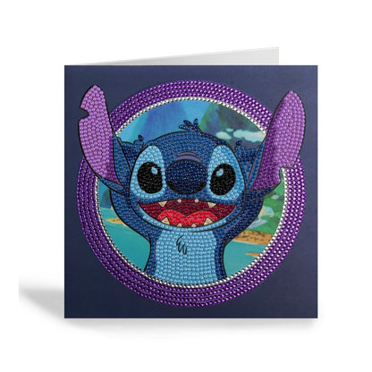 Disney's Stitch is depicted in sparkling blue and purple rhinestones on a square CrystalArt greeting card surrounded by a shimmering crystal ring