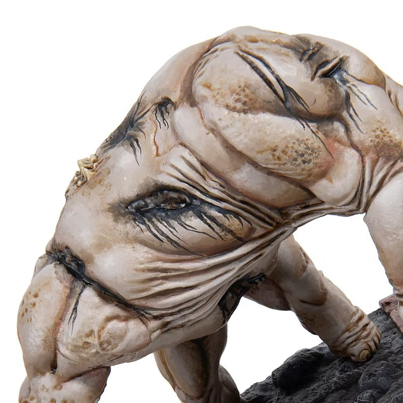 Pale, muscular creature figurine with wrinkled skin and a single dark eye, crouching on a textured black base