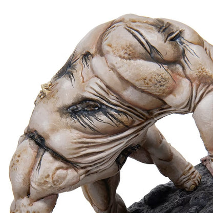 Pale, muscular creature figurine with wrinkled skin and a single dark eye, crouching on a textured black base