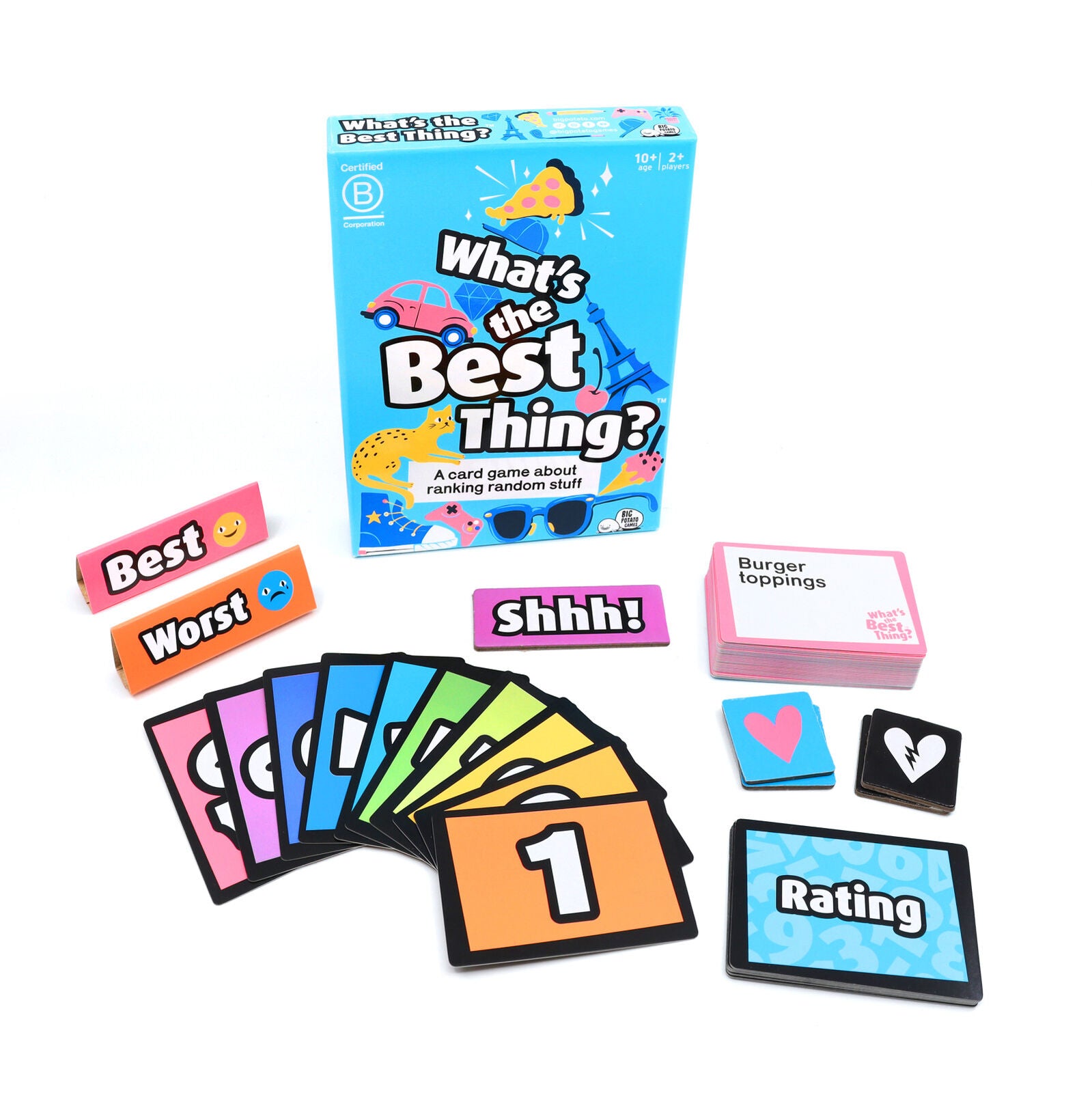 What's the Best Thing card game laid out showing the illustrated blue box, a deck of pink topic cards, colorful numbered ranking cards, and pink and orange tokens
