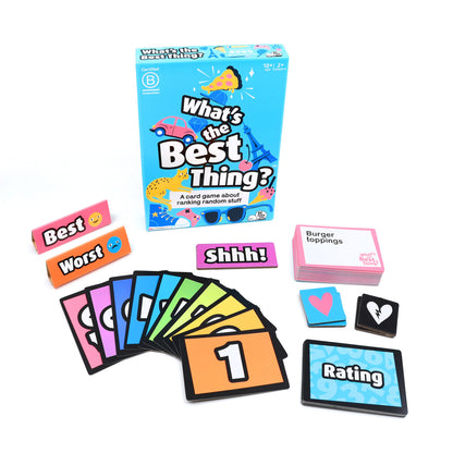 What's the Best Thing card game laid out showing the illustrated blue box, a deck of pink topic cards, colorful numbered ranking cards, and pink and orange tokens