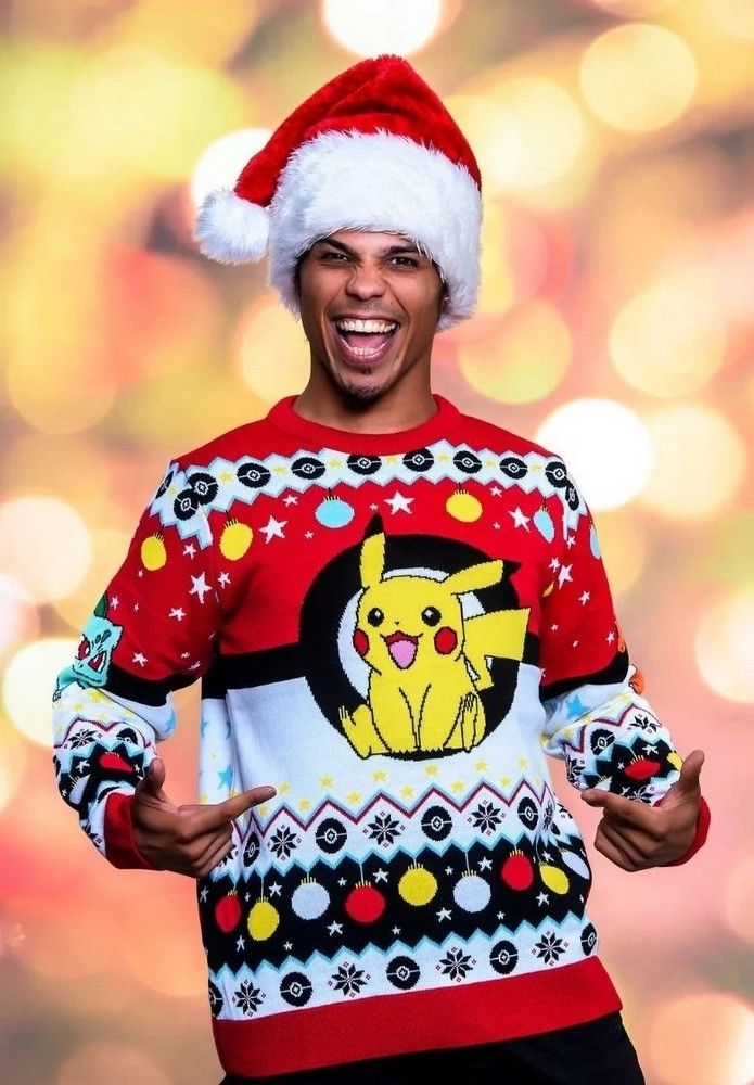 A grinning person in a Santa hat models a red, white, and black ugly Christmas sweater featuring a cheerful Pikachu inside a large Poké Ball design