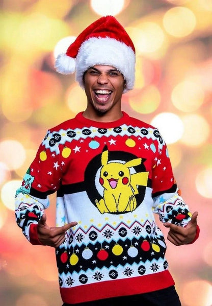A grinning person in a Santa hat models a red, white, and black ugly Christmas sweater featuring a cheerful Pikachu inside a large Poké Ball design